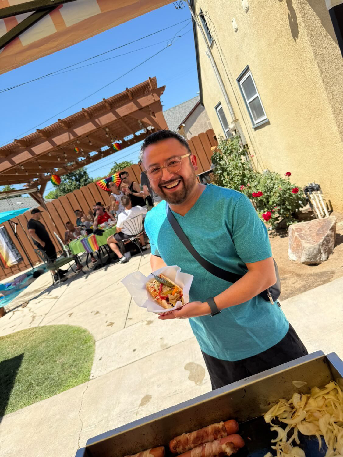 Happy customer smiling at an outdoor event holding a fresh Tower Hotdog