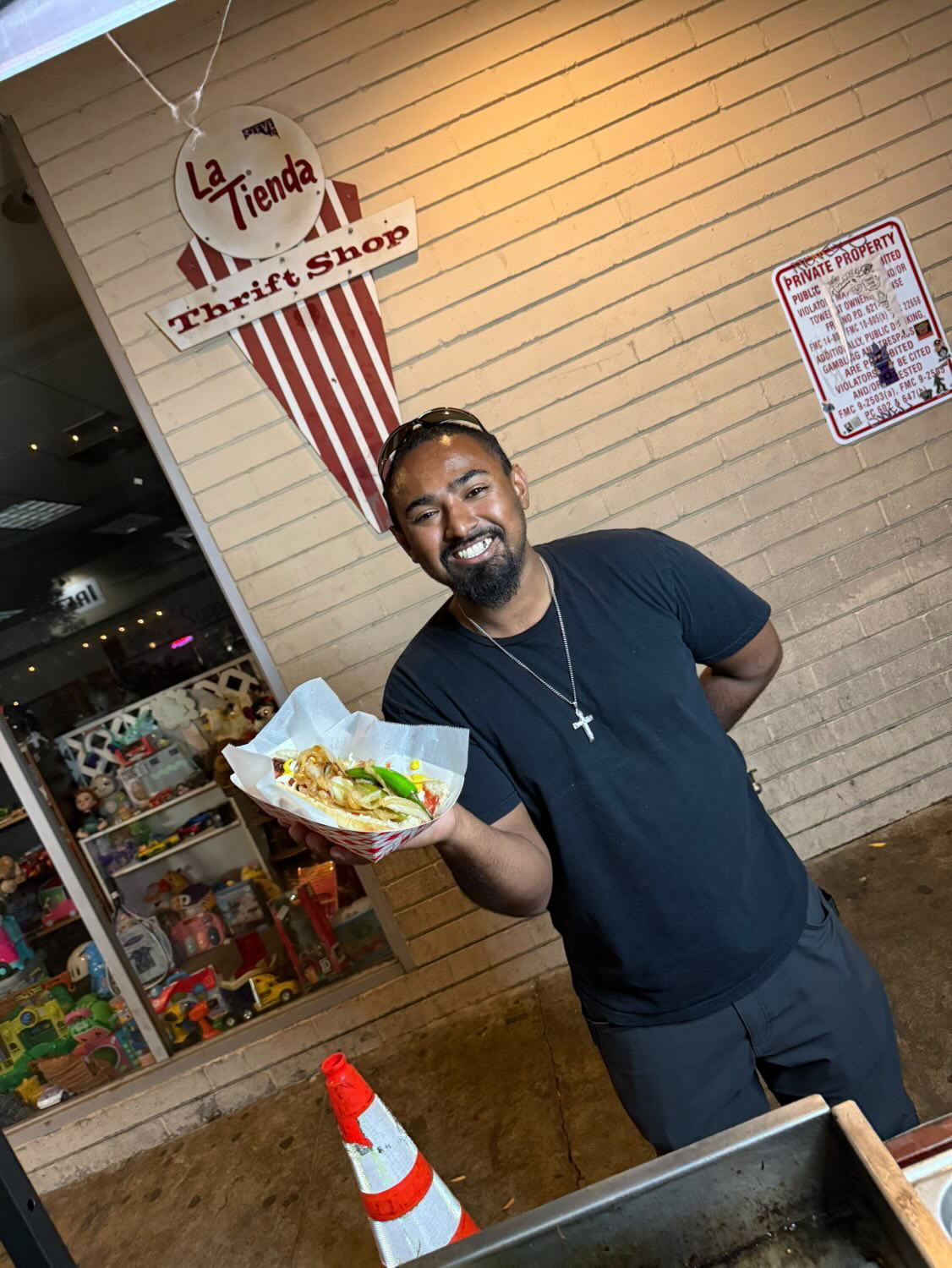 Customer holding a loaded Tower Hotdog outside La Tienda — street approved