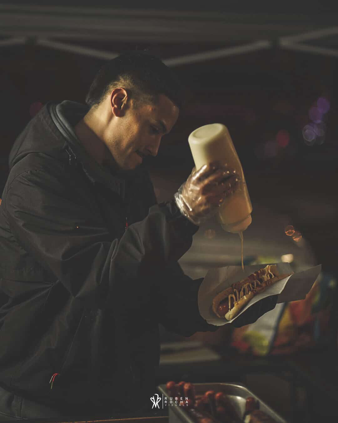 Tower Hotdogs owner drizzling sauce on a fresh build